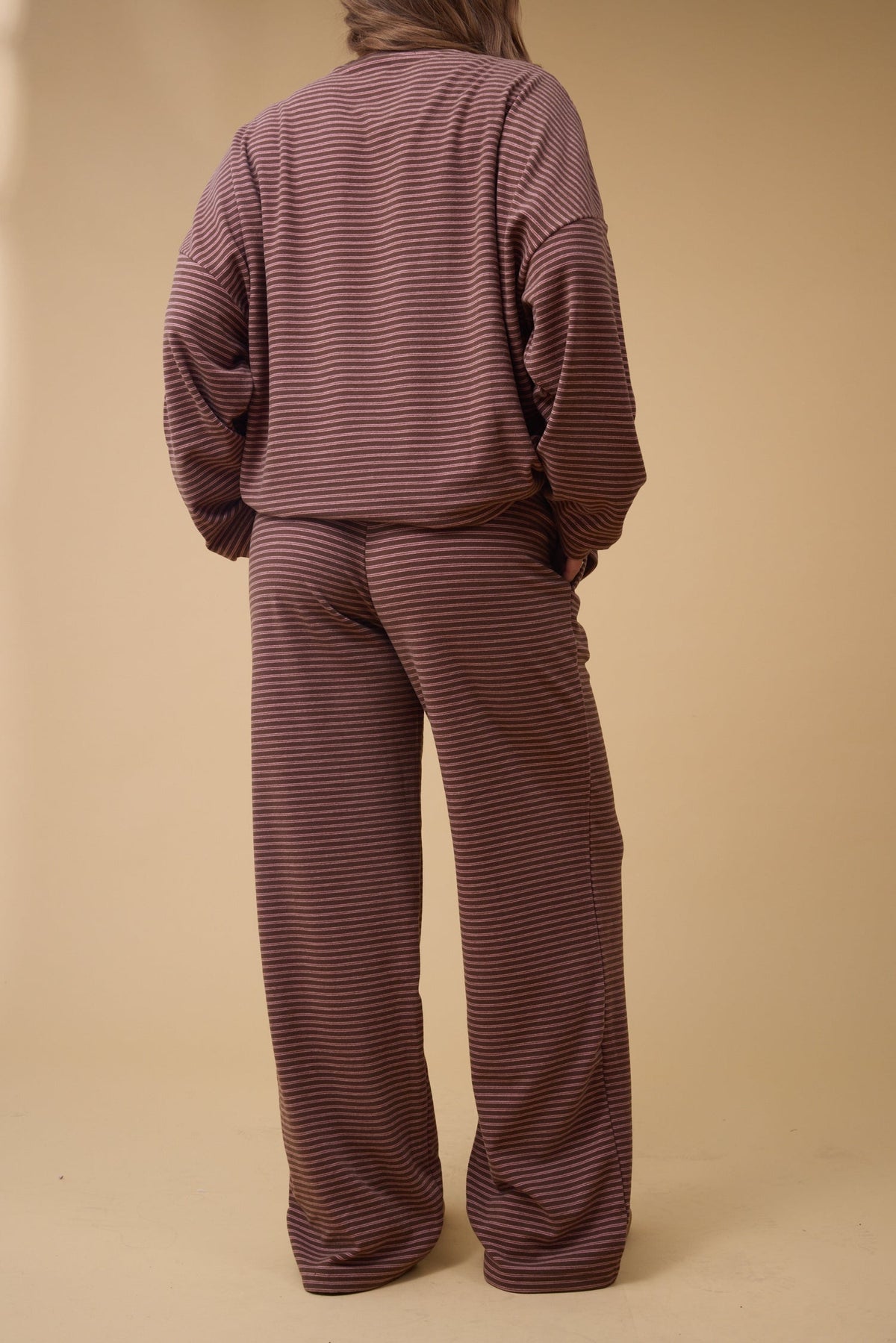Back view of a woman wearing a redish brown stripe lounge set.
