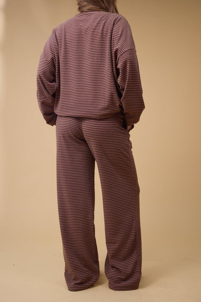 Back view of a woman wearing a redish brown stripe lounge set.