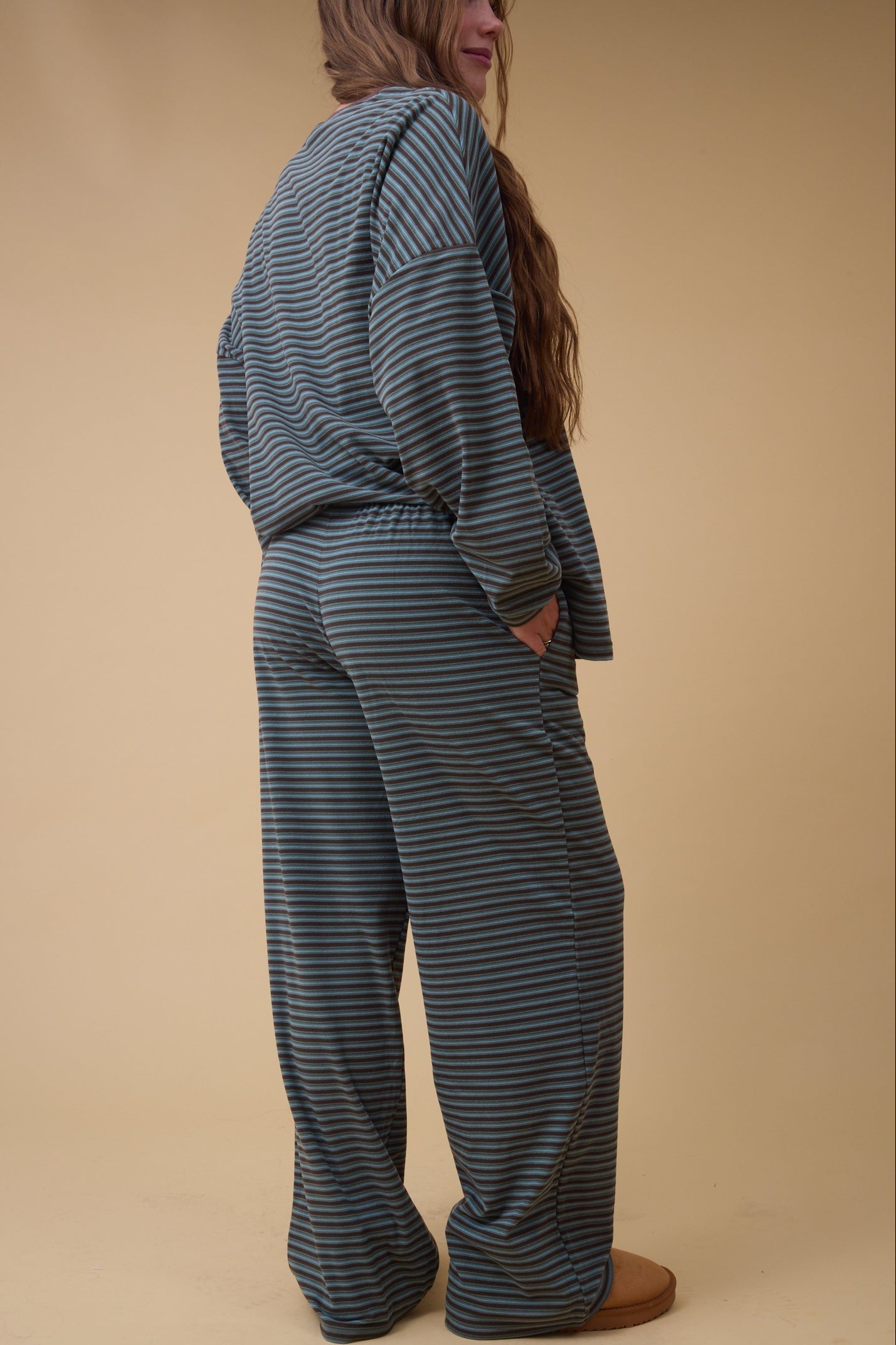 Back view of a woman wearing loose fitting lounge set in teal & brown stripe.