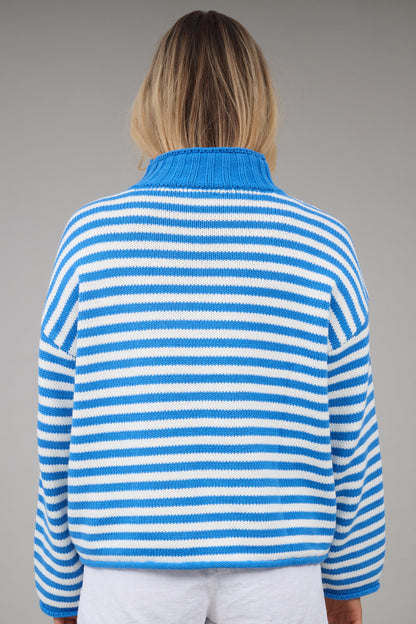 Back view of a woman wearing a loose fitting blue & white stripe sweater.