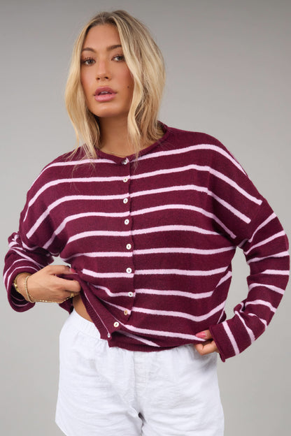 Young woman wearing a modest burgundy & pink button down cardiganwith a rolled collar and long sleeves.