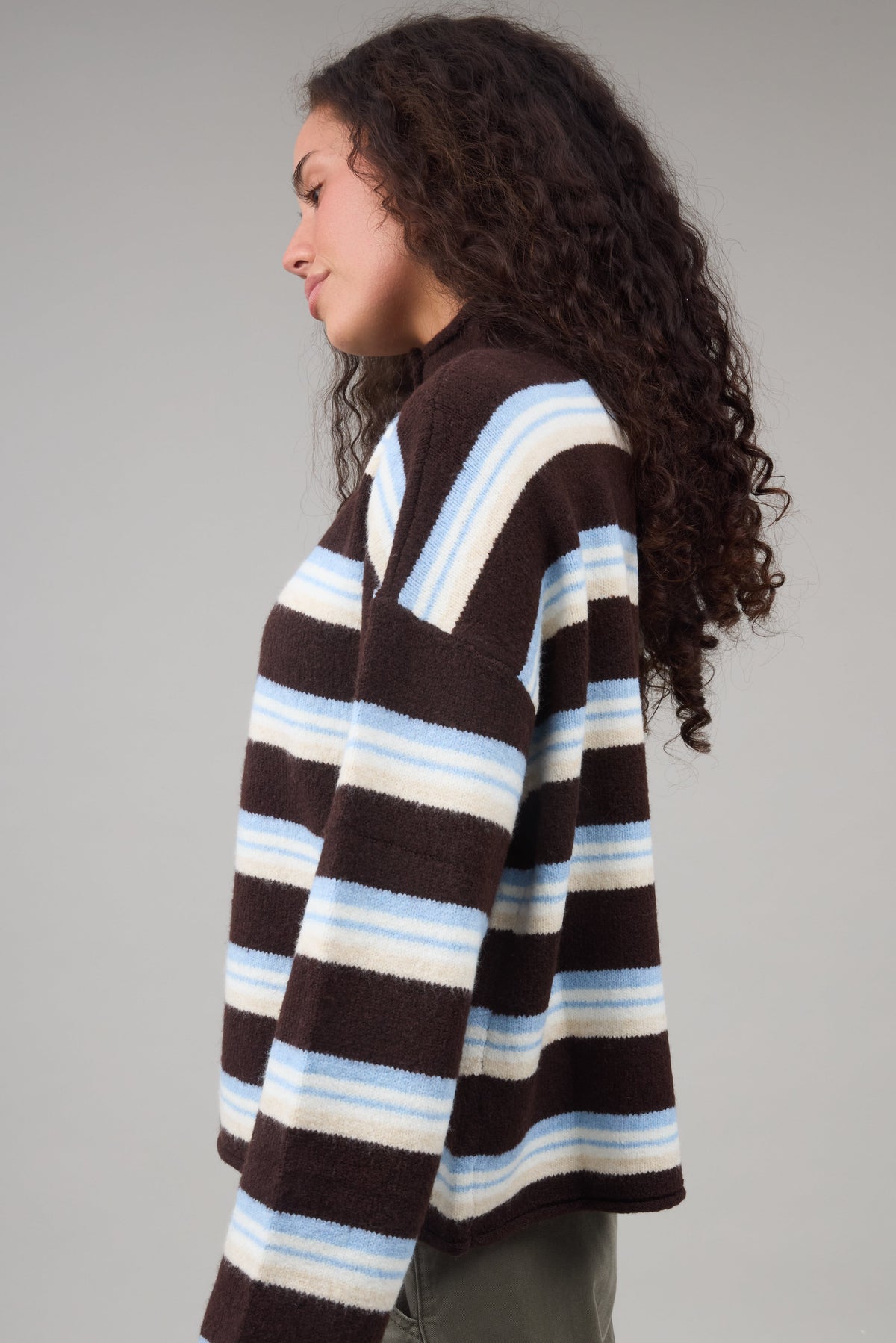 Young woman wearing a brown multi color stripe cardigan with long sleeves.
