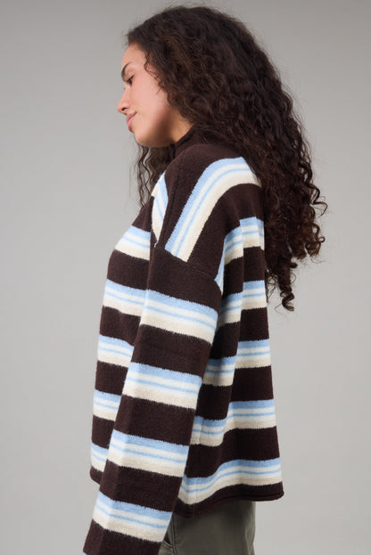 Young woman wearing a brown multi color stripe cardigan with long sleeves.