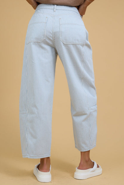 Back view of a woman wearing white & blue stripe, wide leg barrel jeans.