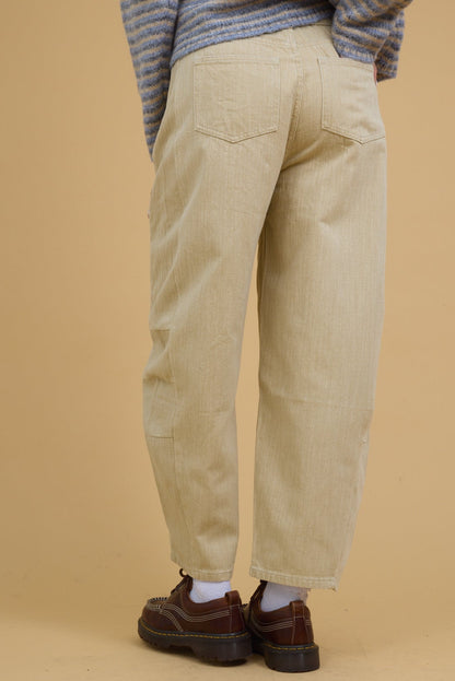 Back view of a woman wearing beige wide leg barrel pants with side panels with sewn in darts.