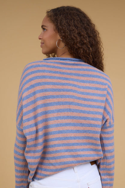 Back view of a woman wearing a loose fitting long sleeve stripe sweater in blush & blue.