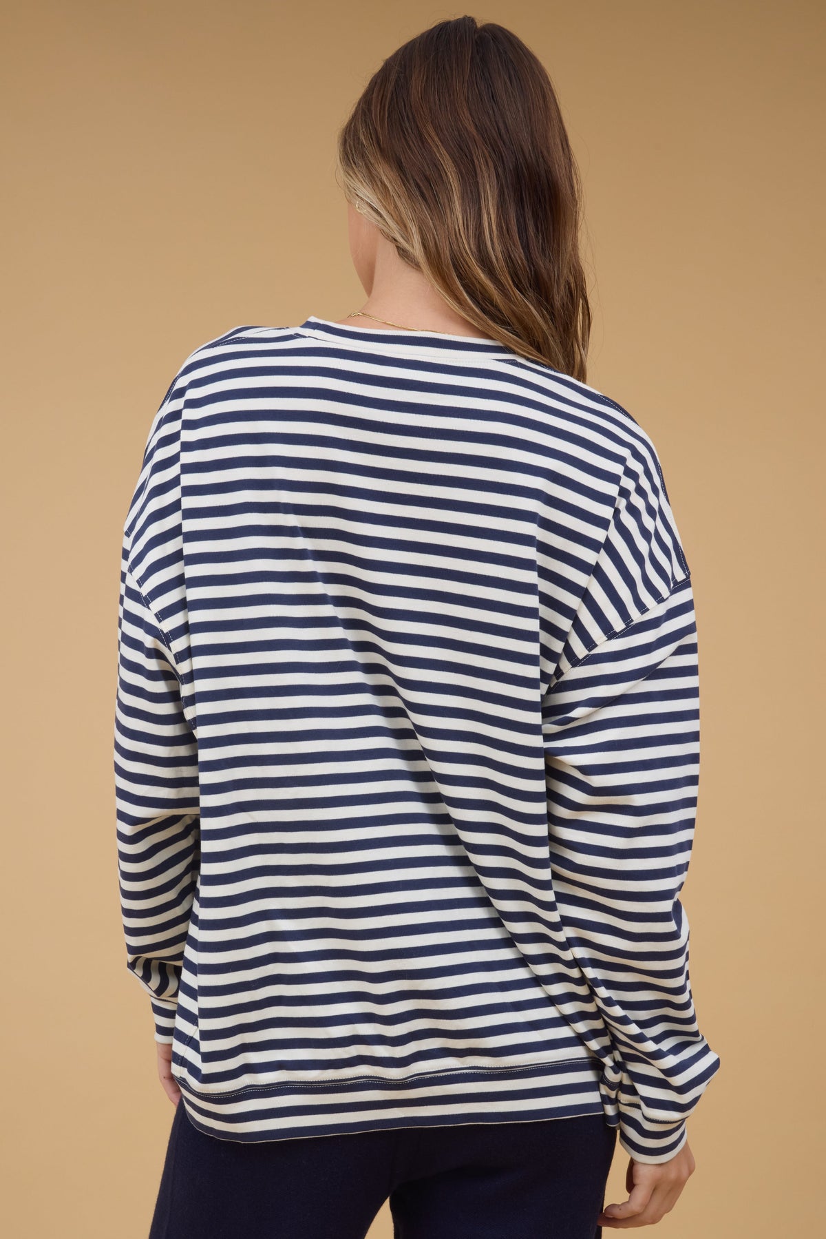 Back view of a woman wearing a very loose fitting top in navy & white stripe.