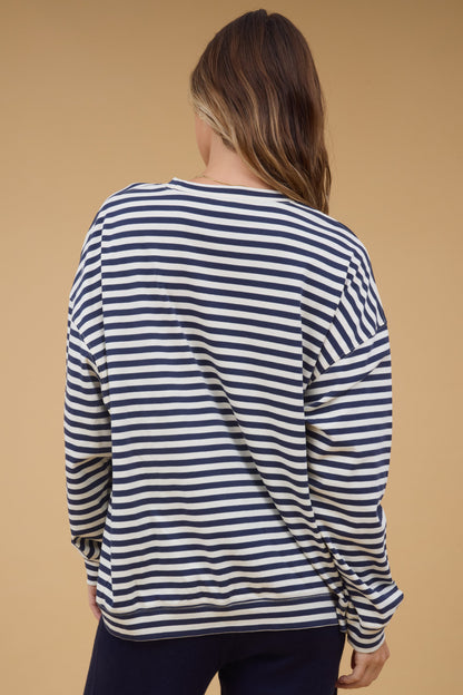 Back view of a woman wearing a very loose fitting top in navy & white stripe.