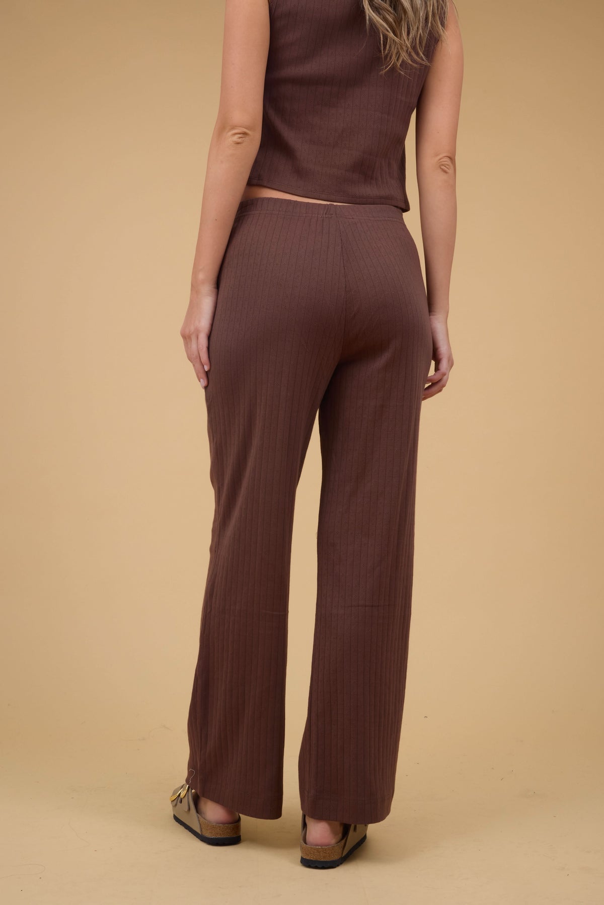 Back view of a woan wearing a pair of brown pointelle knit, wide leg pant.