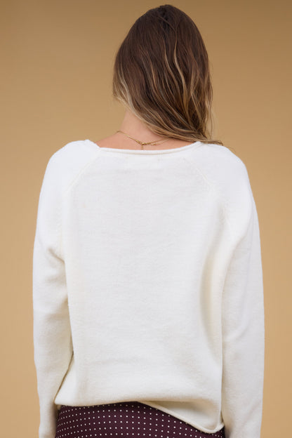 Back view of a woman wearing a cream, long sleeve sweater.