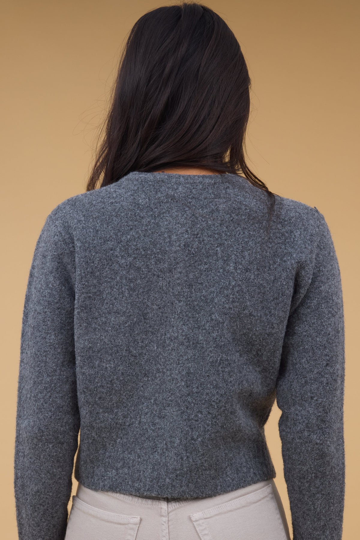 Back view of a woman wearing a charcoal cardigan with long sleeves.