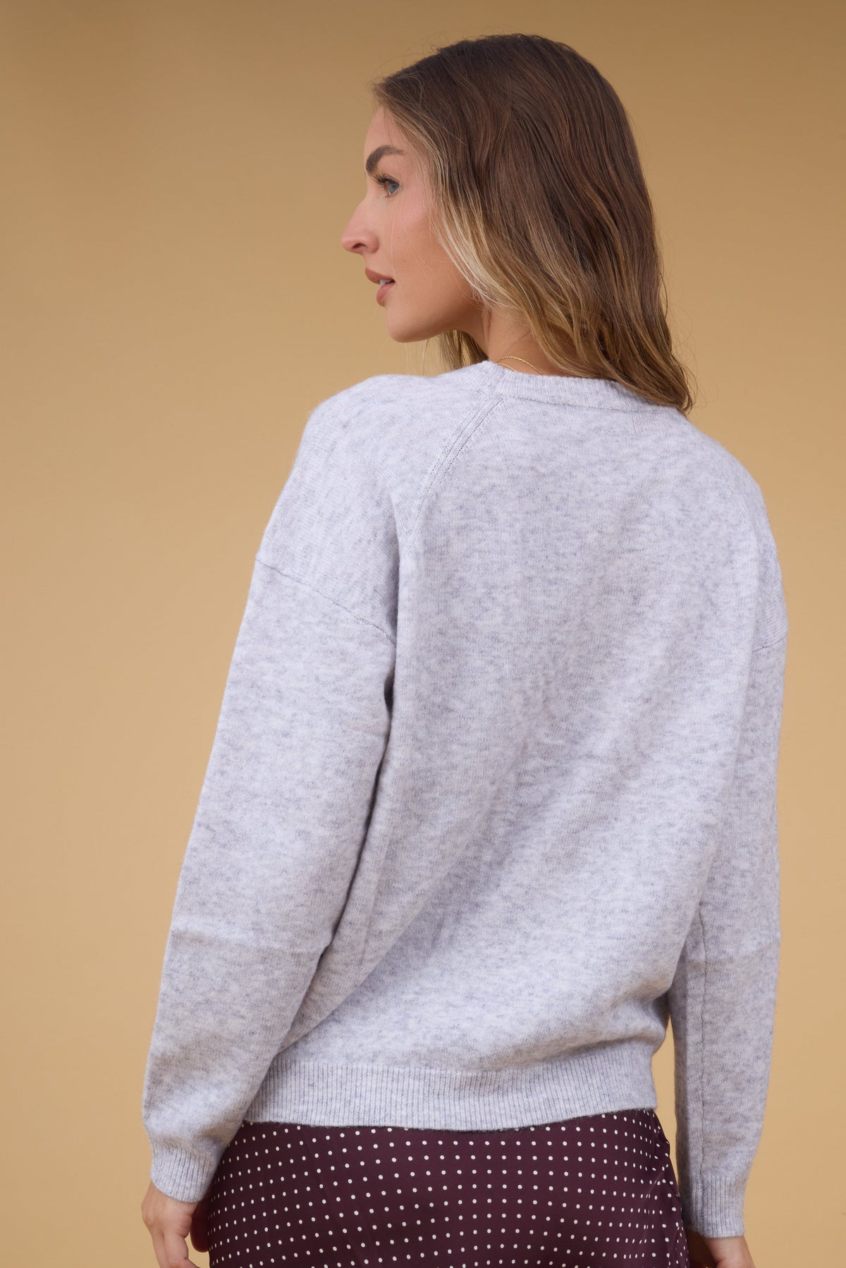 Back view of a woman wearing a soft gry long sleeve sweater.
