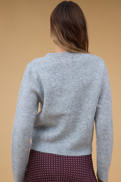 Back view of a woman wearing a grey long sleeve sweater.