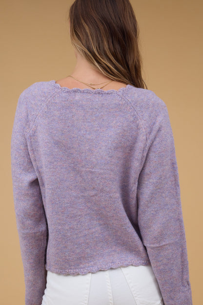 Back view of a woman wearing a lavender cardigan with scallop hems.