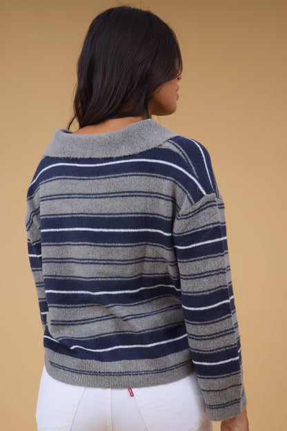 Back view of a woman wearing a grey  navy stripe sweater with long sleeve.