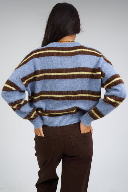 Back view of a woman wearing a loose fitting blue  stripe pullover sweater with long sleeves.