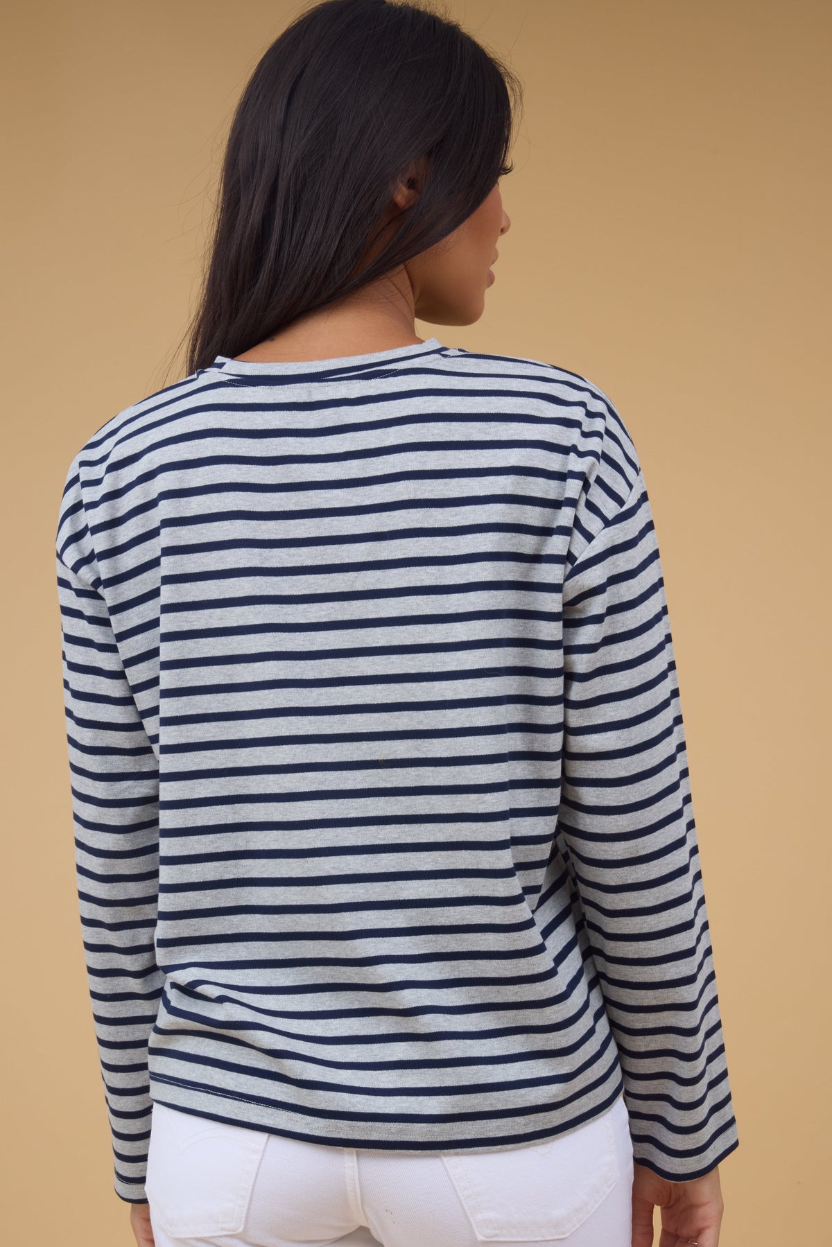 Back view of a woman wearing a grey & navy stripe, long sleeve tee.