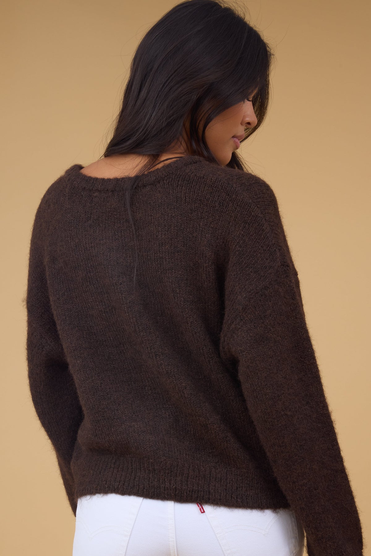 Back view of a woman wearing a long sleeve brown cardigan.