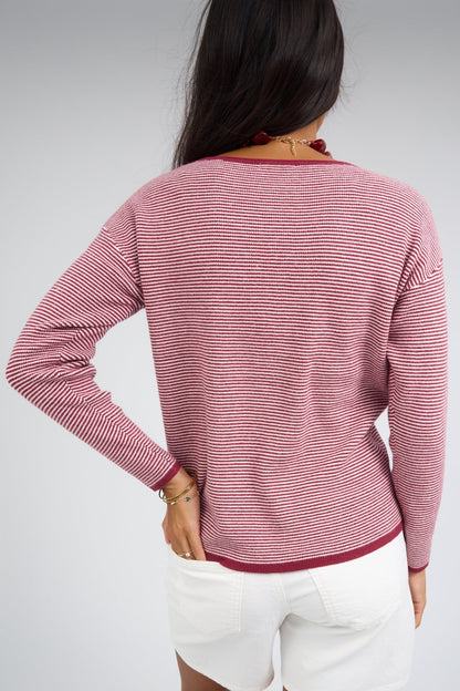 Back view of a woman wearing a burgundy & white stripe top with long sleeves and a round neckline.