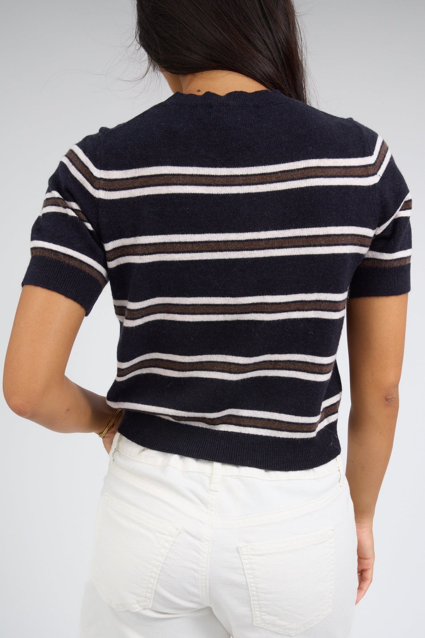 Woman wearing a navy, brown, and white stripe short sleeve sweater.