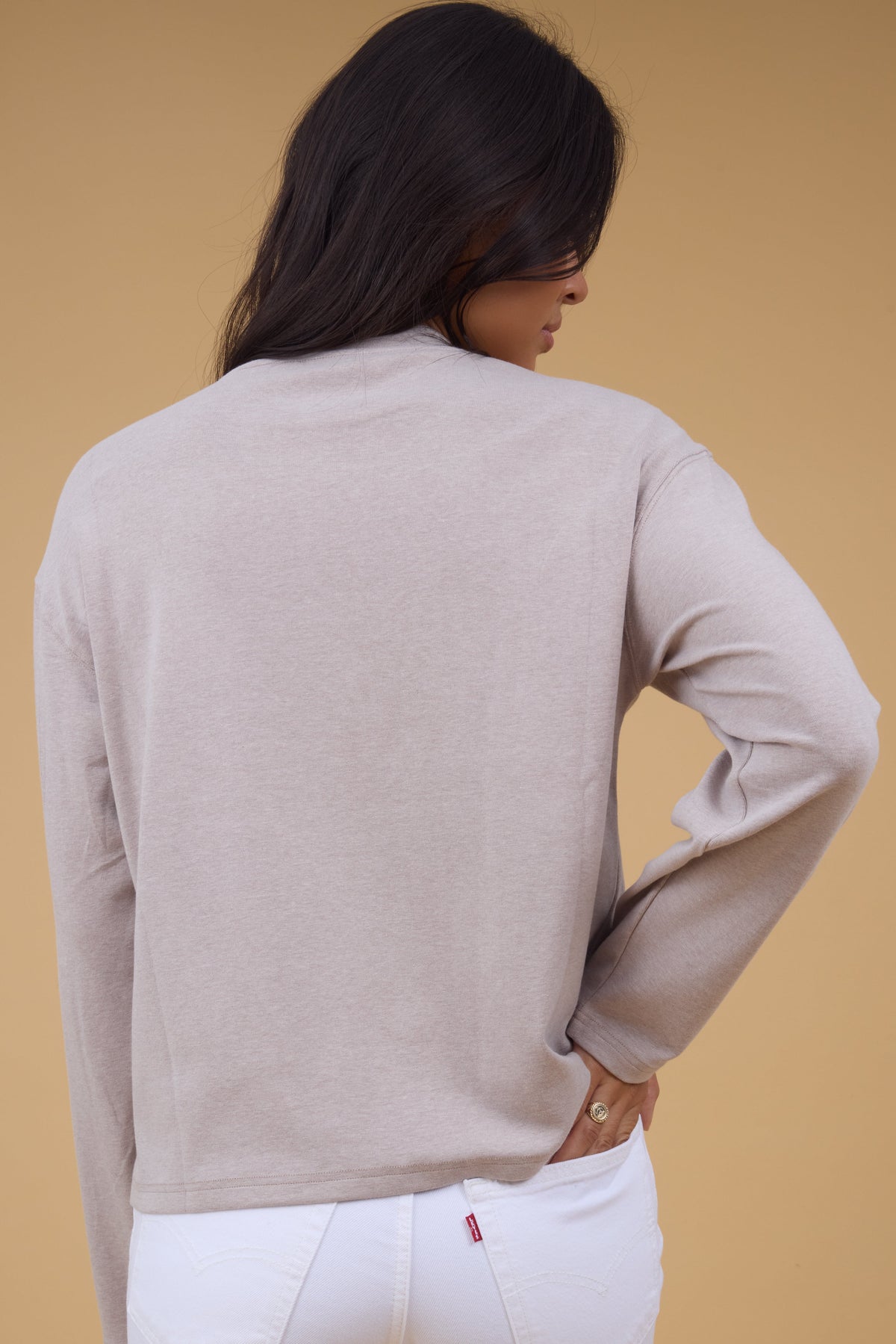 Tbe back view of a young woman wearing a soft long sleeve knit top taupe for women and teen girls.