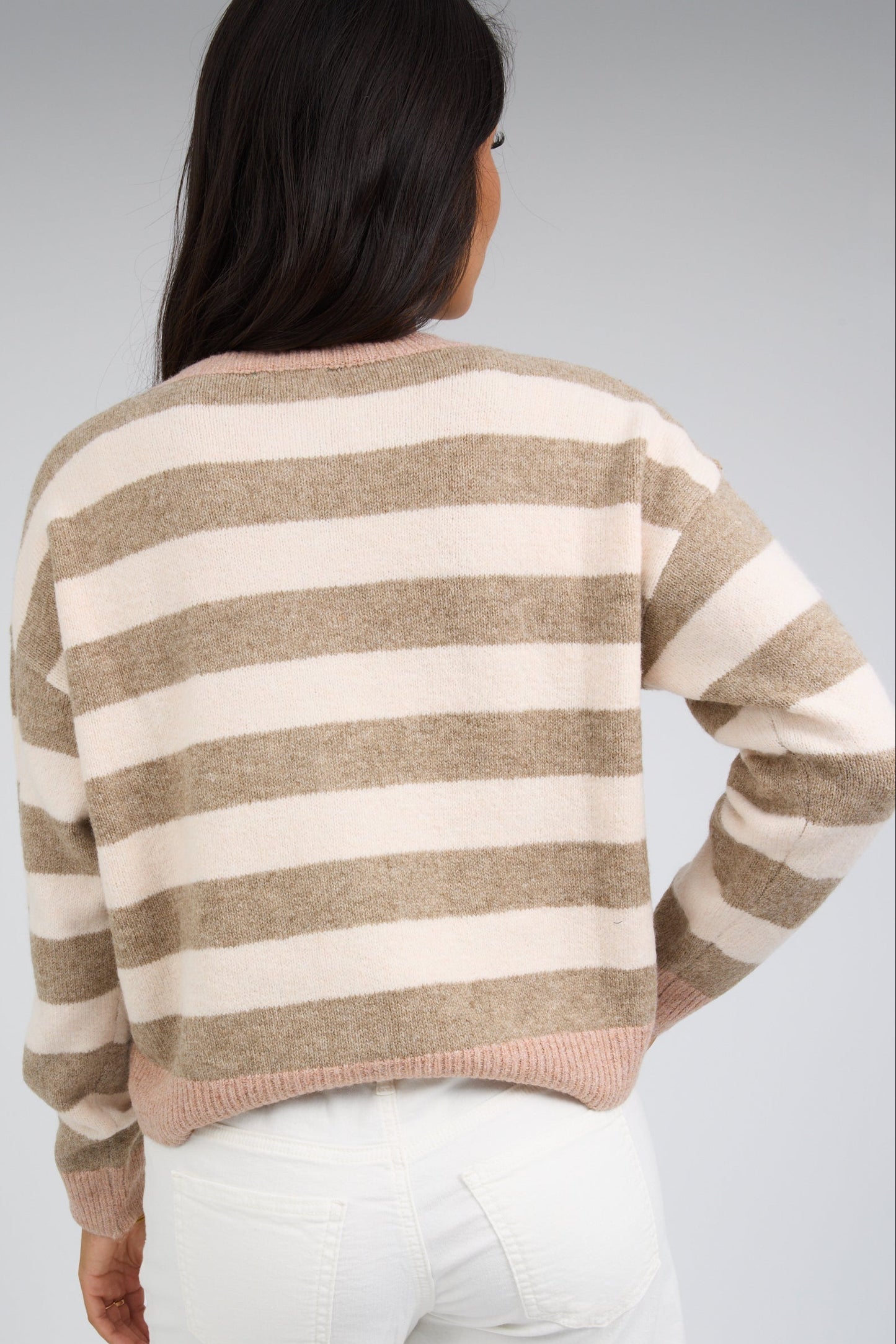 Back view of a woman wearing a light brown and cream stripe cardigan with long sleeves.