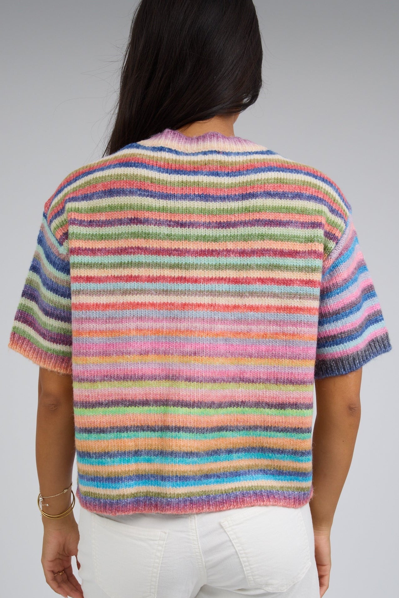 Back view of a woman wearing a rainbow stripe cardigan with short sleeves.