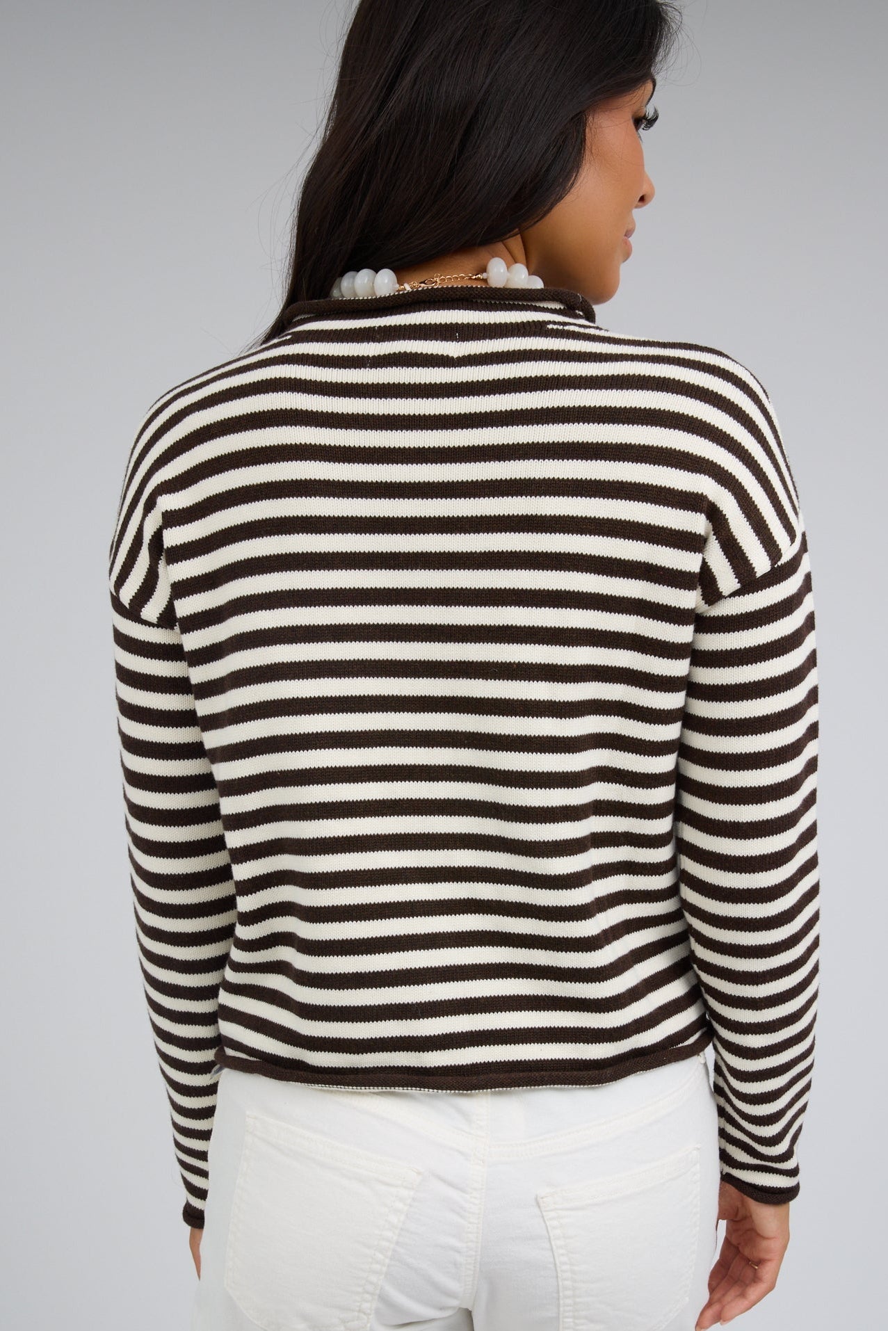 Back view of a woman wearing a brown & white stripe cardigan with long sleeves.