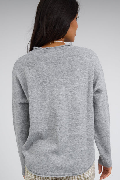Back view of a young woman wearing a heather grey pullover sweater with long sleeves.