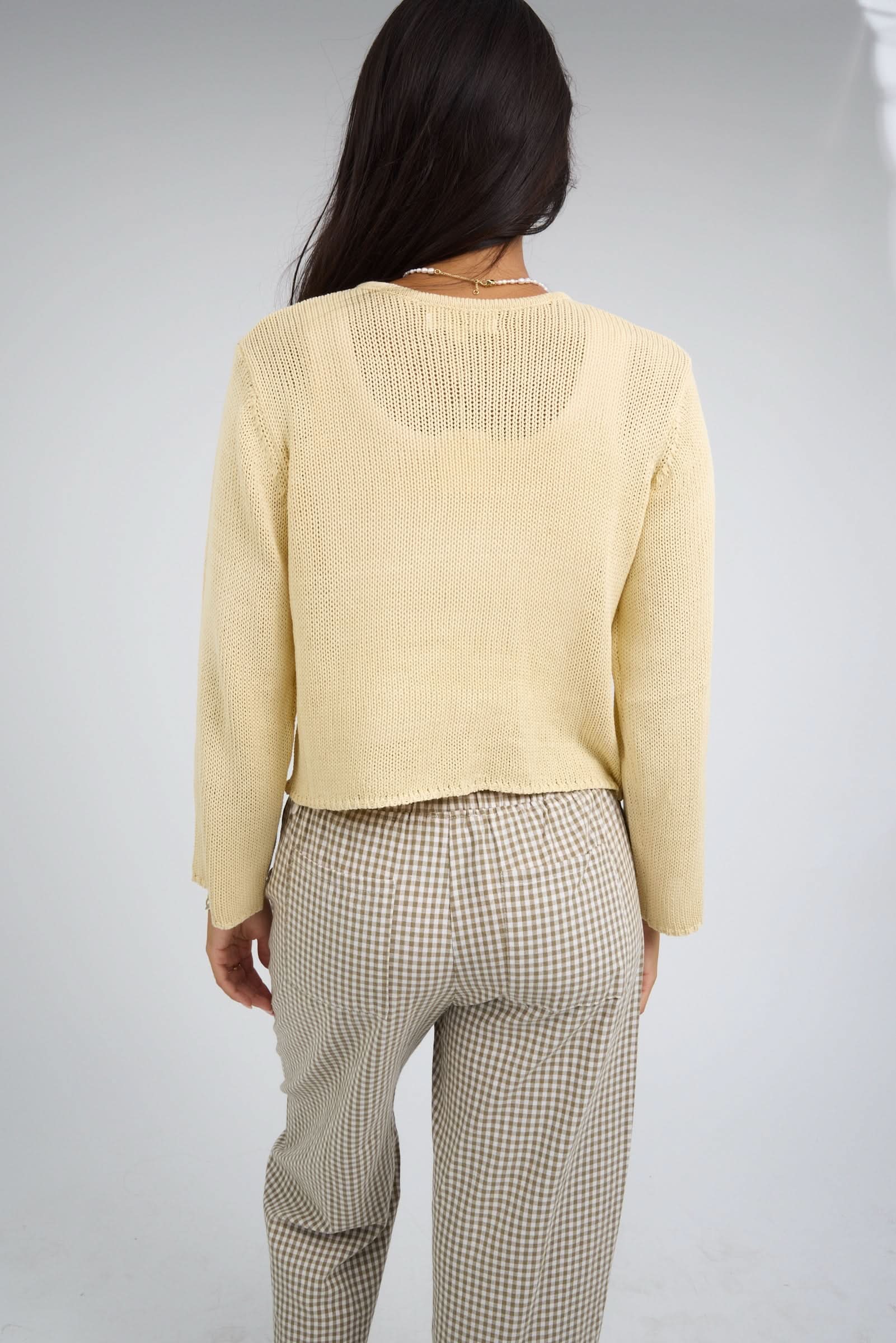 Back view of a woman wearing a yellow cardigan with long sleeves.