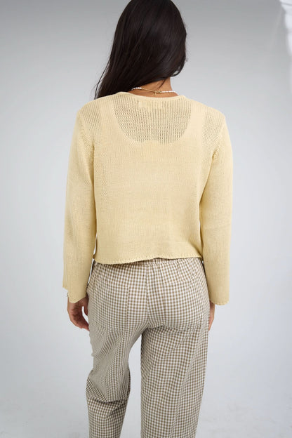 Back view of a woman wearing a yellow cardigan with long sleeves.