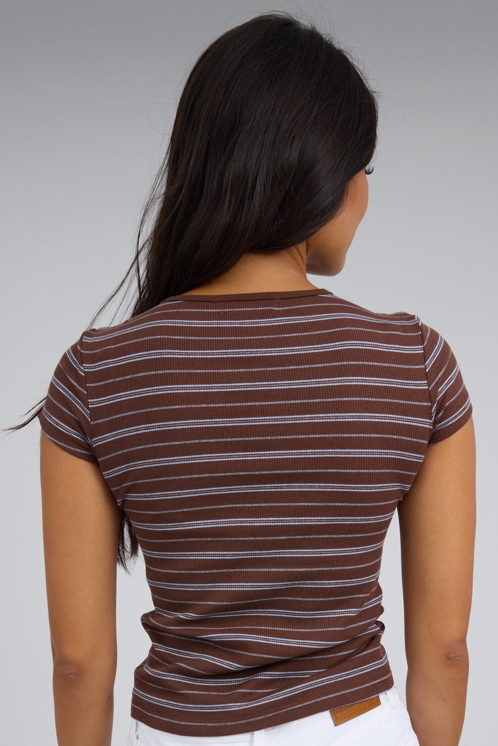Back view of a woman wearing a brown stripe rib knit close fitting tee with short sleeves.
