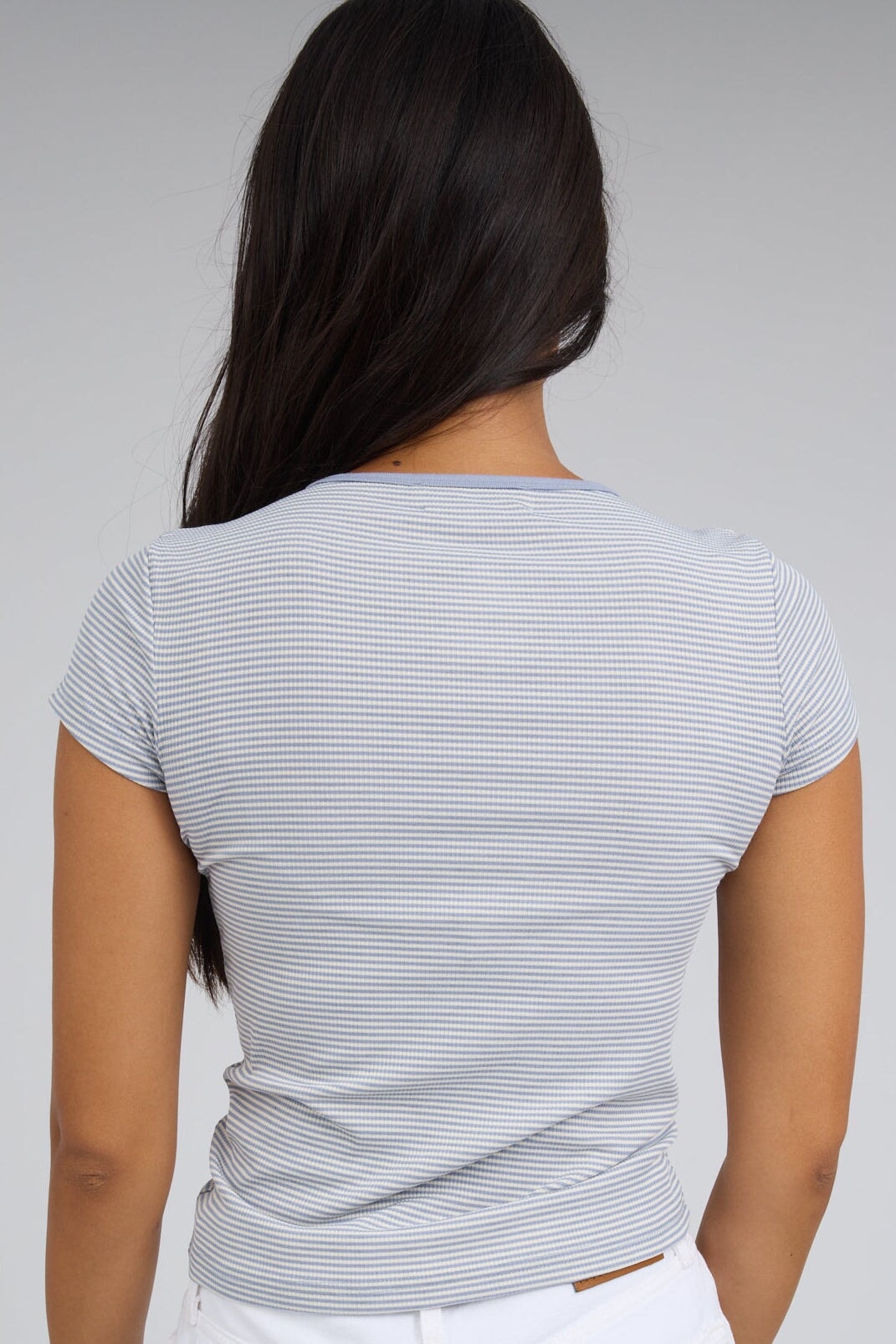 Back view of a woman wearing a blue & white stripe close fitting stretchin tee with short sleeves.