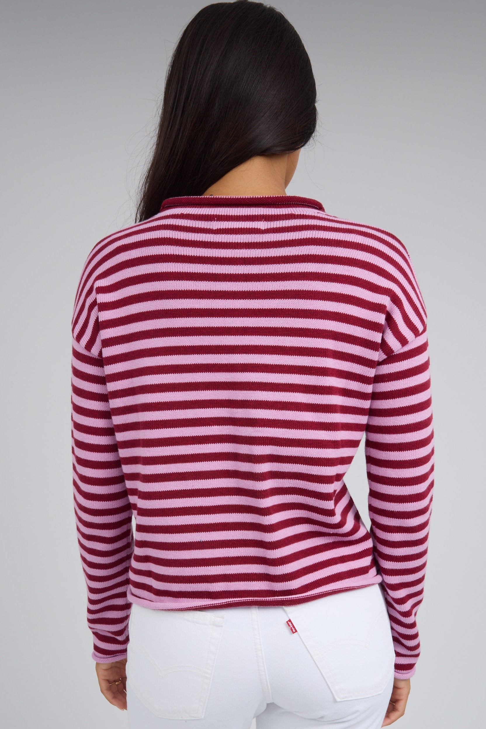 Back view of a woman wearing a pink & red stripe cardigan with long sleeves.