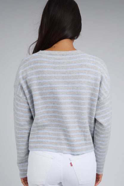 Back view of a woman wearing a grey & light blue stripe cardigan with long sleeves.