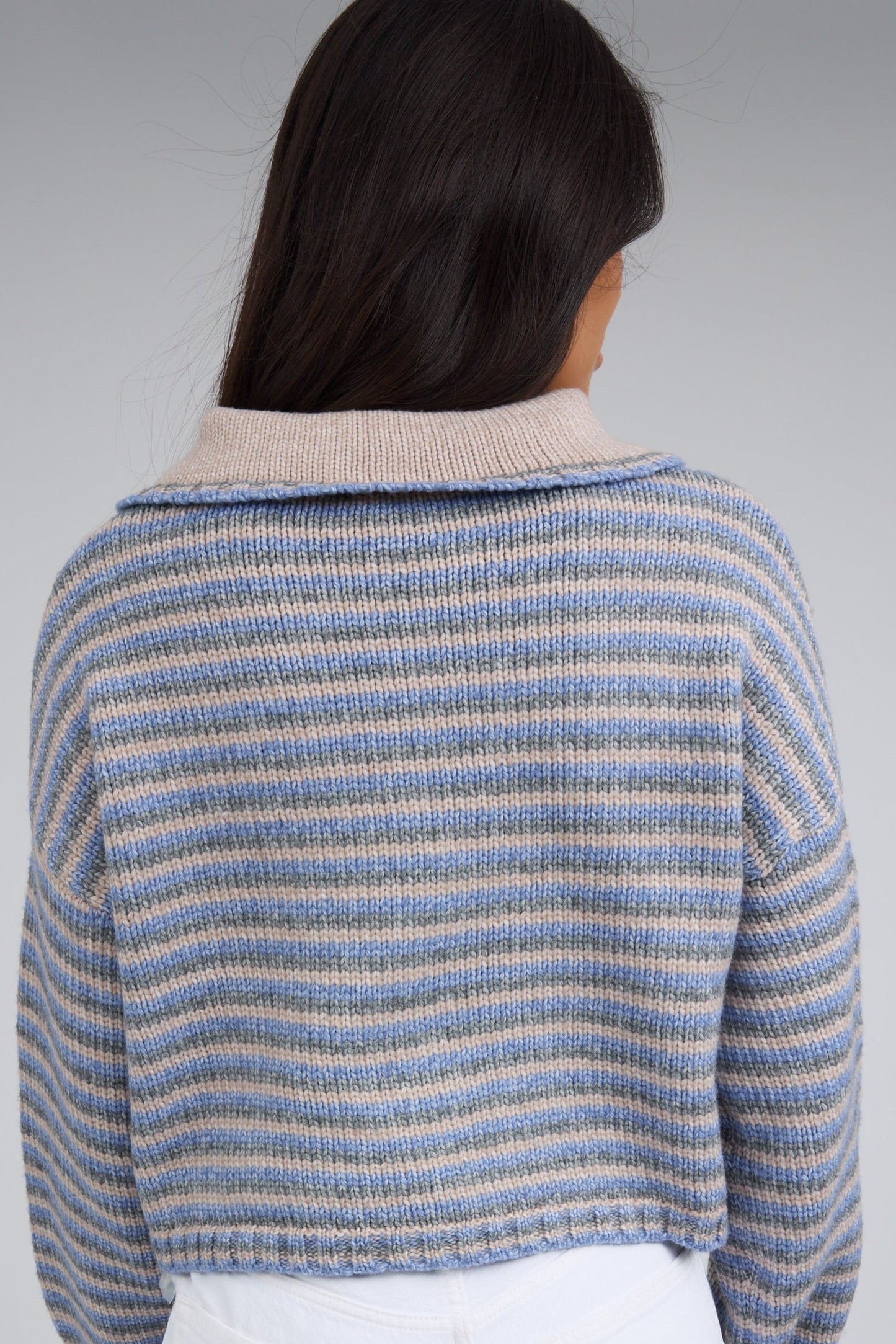 Back view of a woman wearing a blue-taupe multi stripe with a taupe collar.