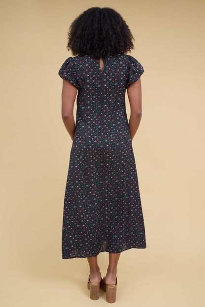 Back view of a woman woman wearing a black floral midi dress with gathered cap sleeves.