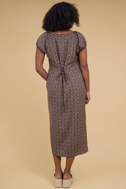 Back view of a woman wearing an olive midi dress  with short puff sleeves and back lacing details to adjust fit.