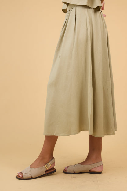 Side view of a woman wearing an olive midi skirt with front pleats.