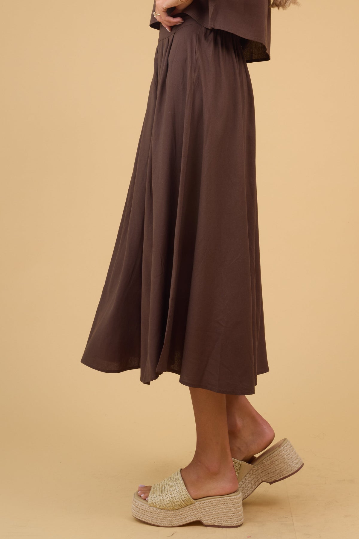 Side view of a woman weairng a flowy brown midi skirt.