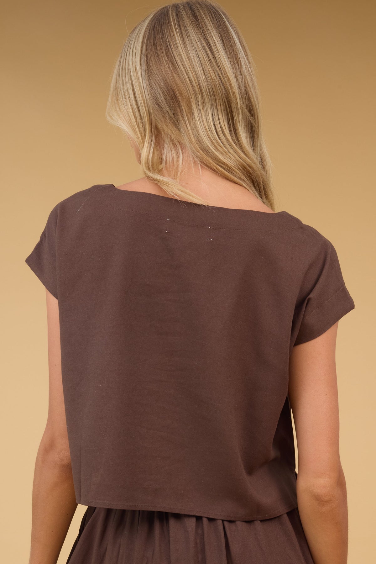 Back view of a woman wearing a frown blouse with cap sleeves.