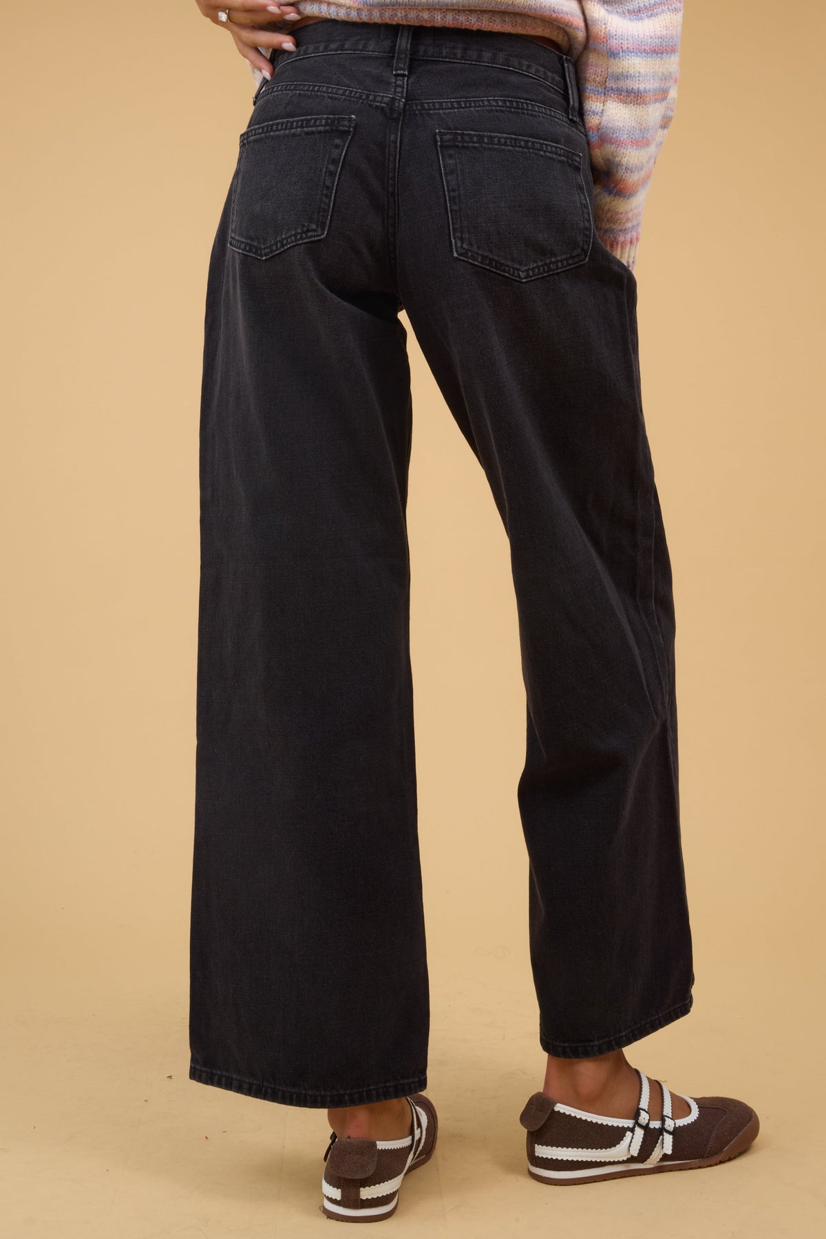 Back view of a woman wearing a washed black wide leg jeans.