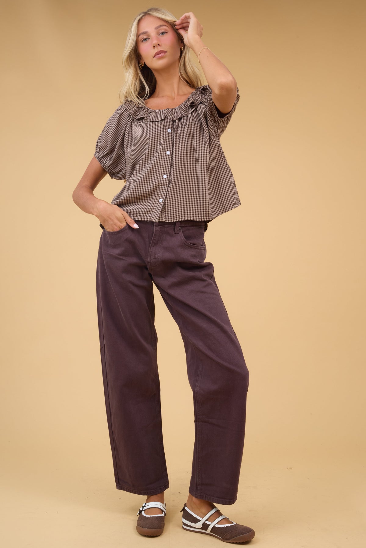 Young woman wearing a pair of wide leg brown jeans with 5 pocktes and zipper/button closure.