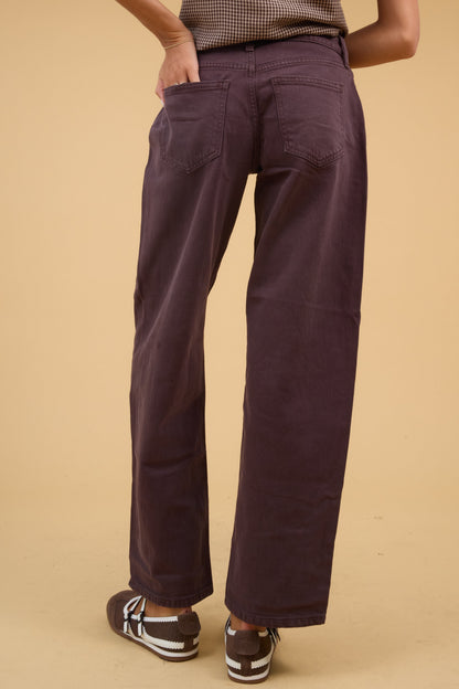 Back view of a young woman wearing a pair of brown wide leg jeans with back patch pockets.