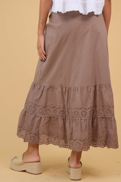 Back view woman wearing a brown eyelet skirt with a botton ruffle.