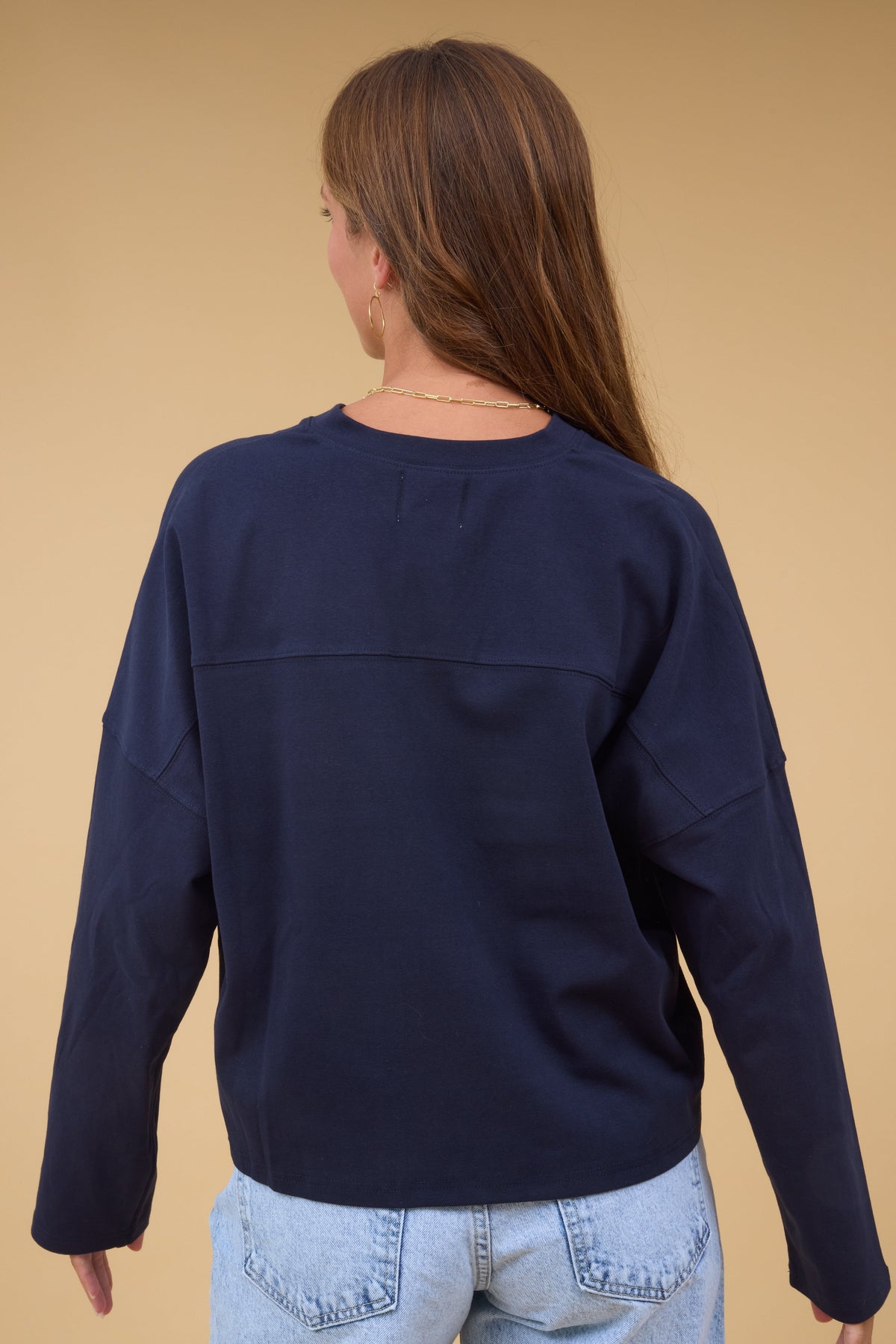 Back view of a woman wearing a navy long sleeve loose fitting tee.