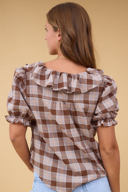 Back view of a woman wearing a loose fitting, brown plaid blouse with a ruffle collar and short puff sleeves.