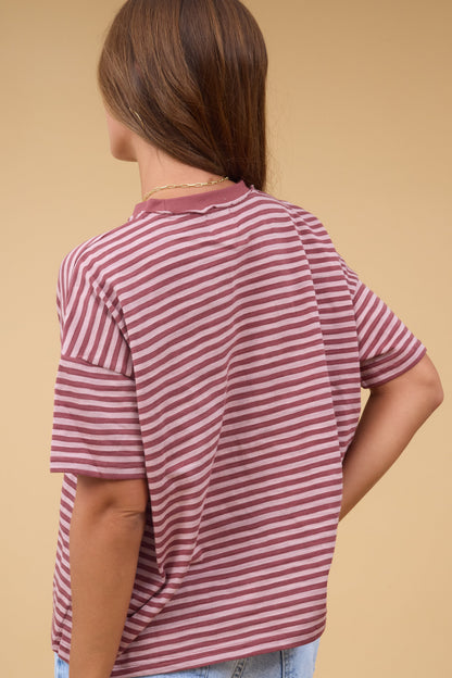 Back view of a woman wearing a loose fitting mauve stripe tee with short sleeves.