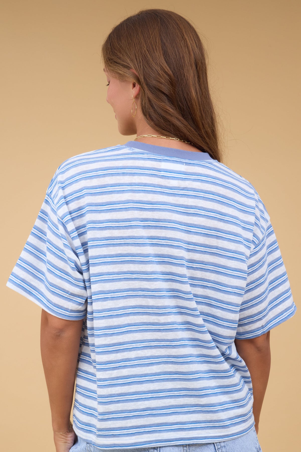 Back view of a woman wearing a white & blue stripe short sleeve tee.