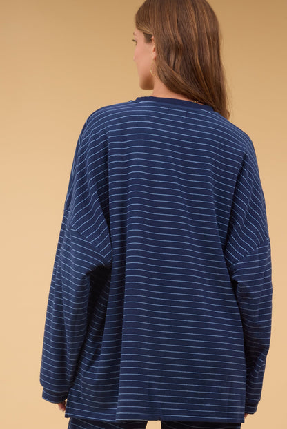 Back view of a young woman wearing an oversized navy stripe lounge top.